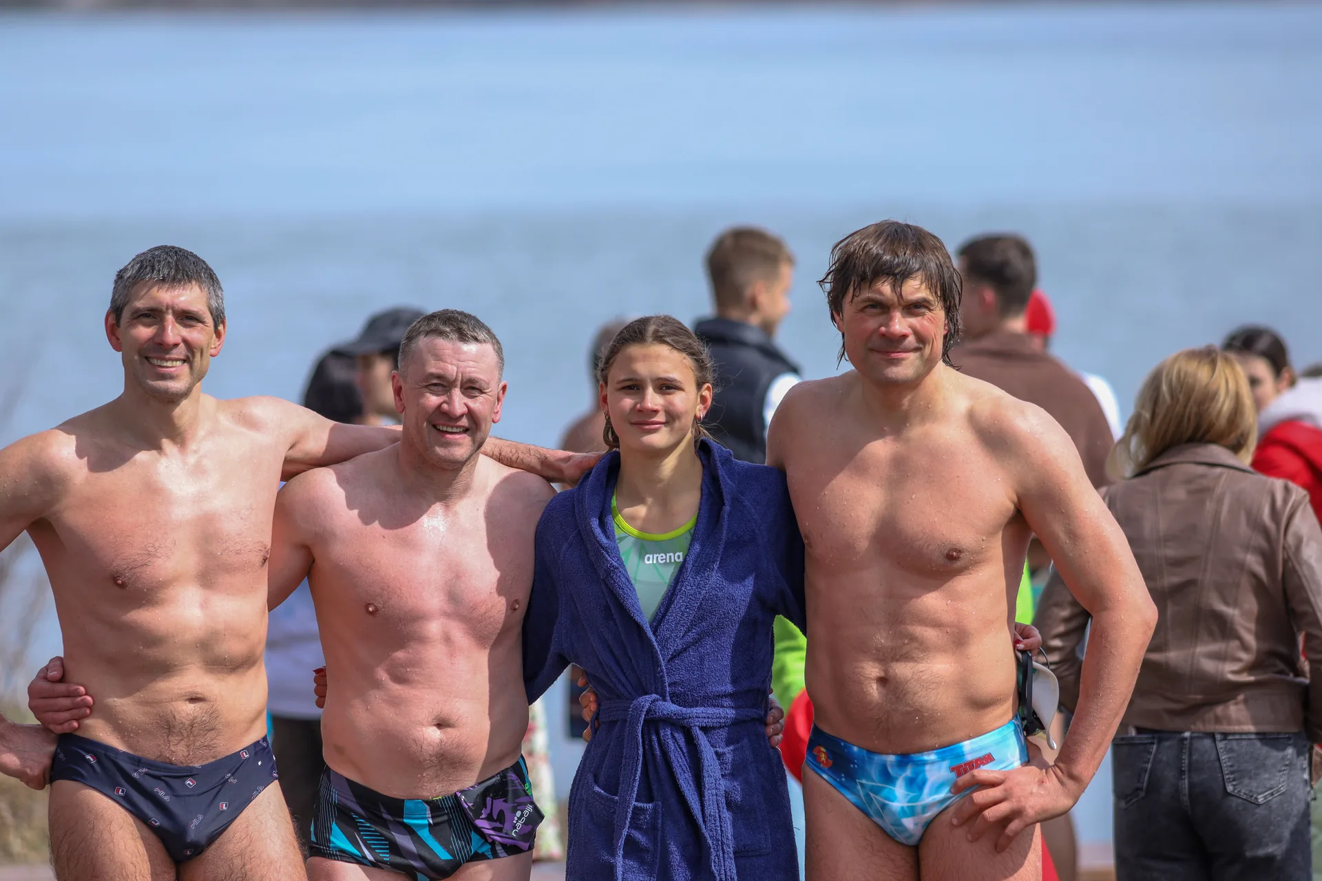 Улыбающиеся участники после заплыва у воды